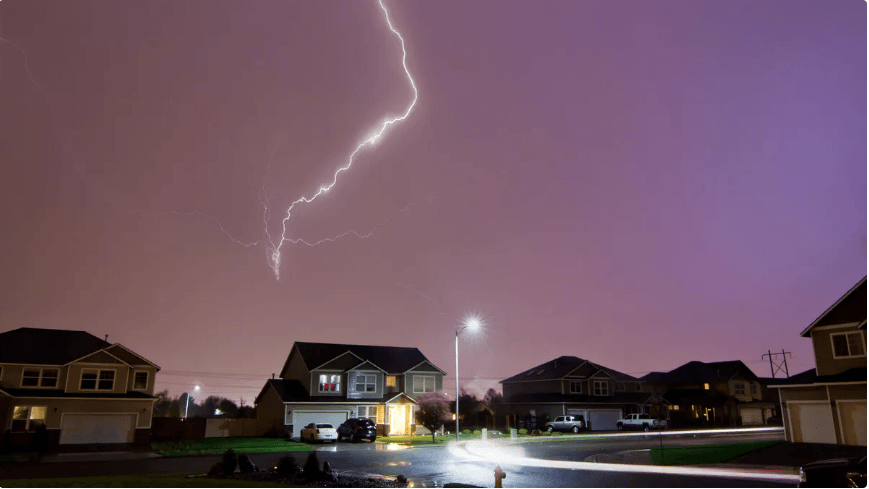Lightning about to strike a house in a neighborhood
